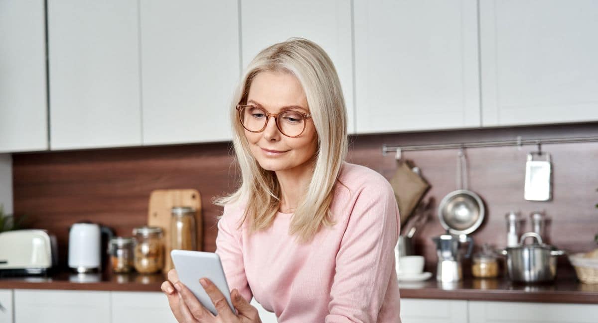 mature woman looking at her phone for her period tracker